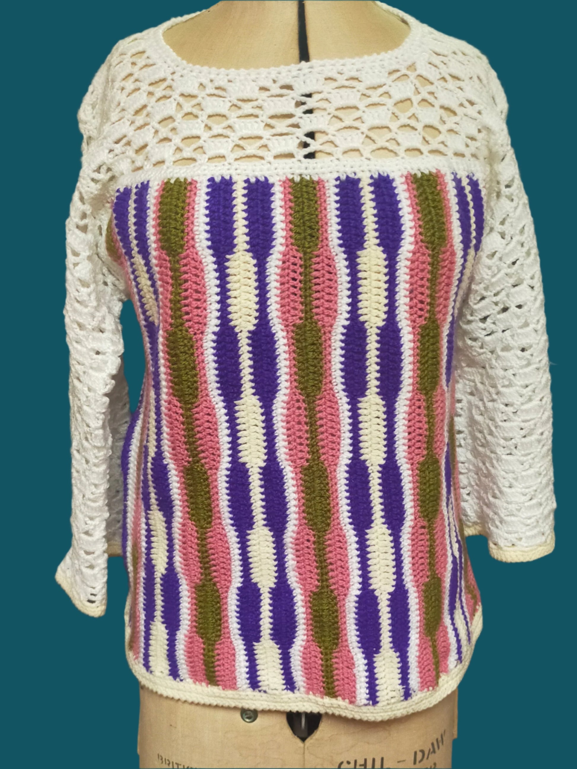 This is a crocheted sweater. The yoke and sleeves are lace crochet, and the body has multi-coloured vertical stripes. It was made by Not Your Nana in Dunedin, New Zealand.