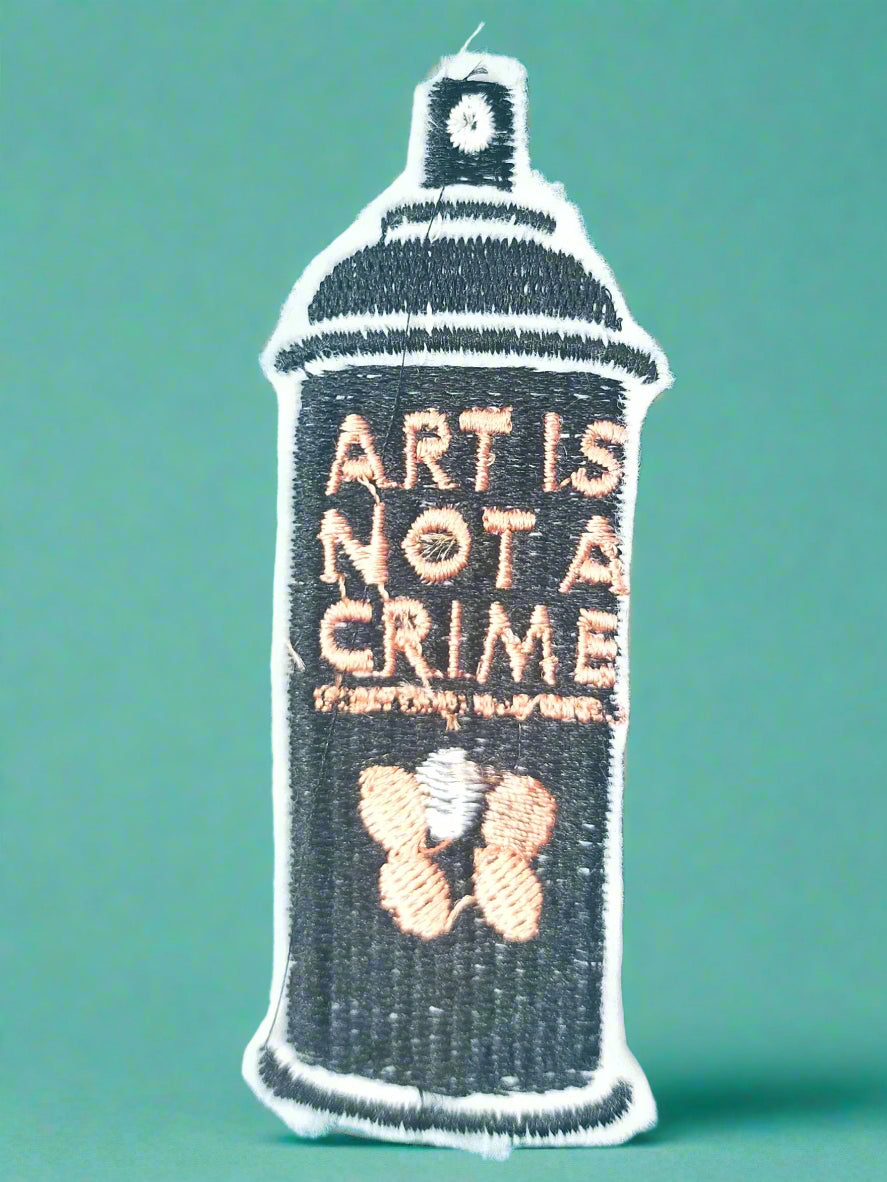 Embroidered patch of a spray can with 'Art is Not a Crime' text on a green background. Made by Not Your Nana in Dunedin, New Zealand.