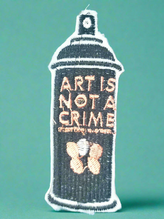 Embroidered patch of a spray can with 'Art is Not a Crime' text on a green background. Made by Not Your Nana in Dunedin, New Zealand.