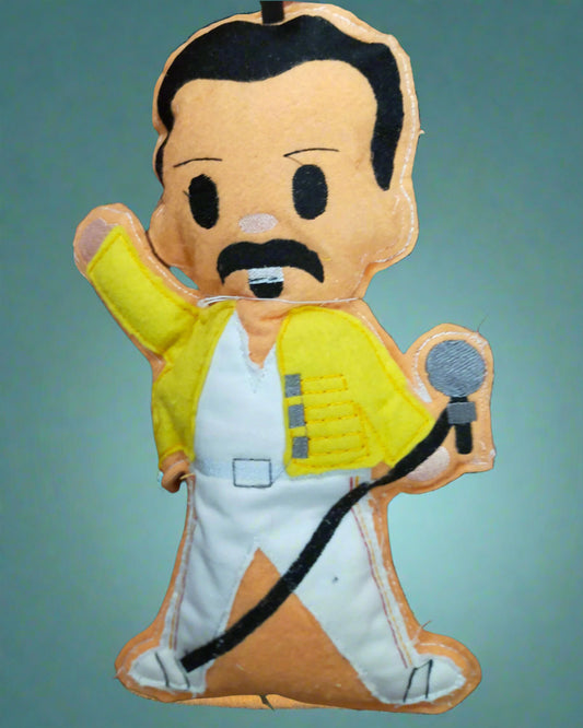 Toy figure of Freddie Mercury in a yellow jacket and white pants on a tiled floor