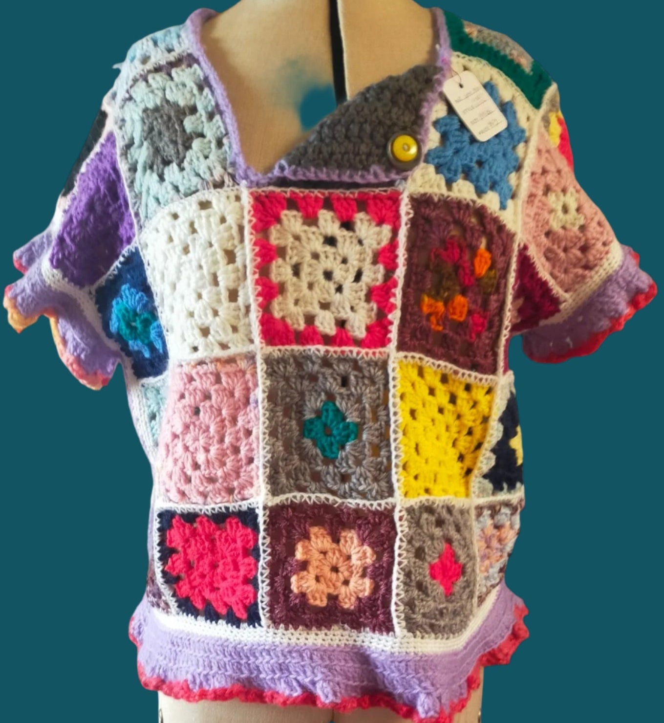 This is a multi-coloured crocheted peggy square top with an interesting neckline. Made by Not Your Nana in Dunedin, New Zealand.