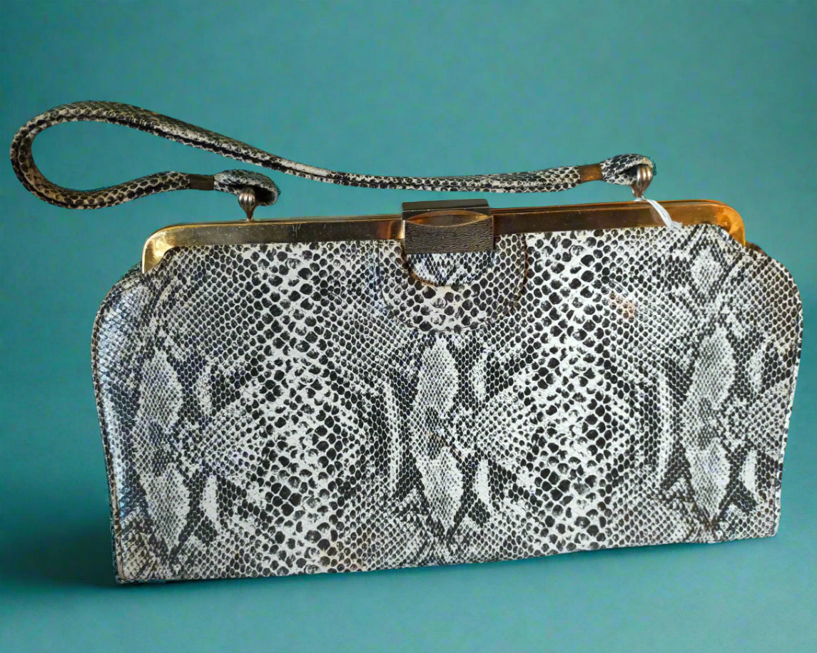 Snake print clutch bag with a gold clasp on a white background