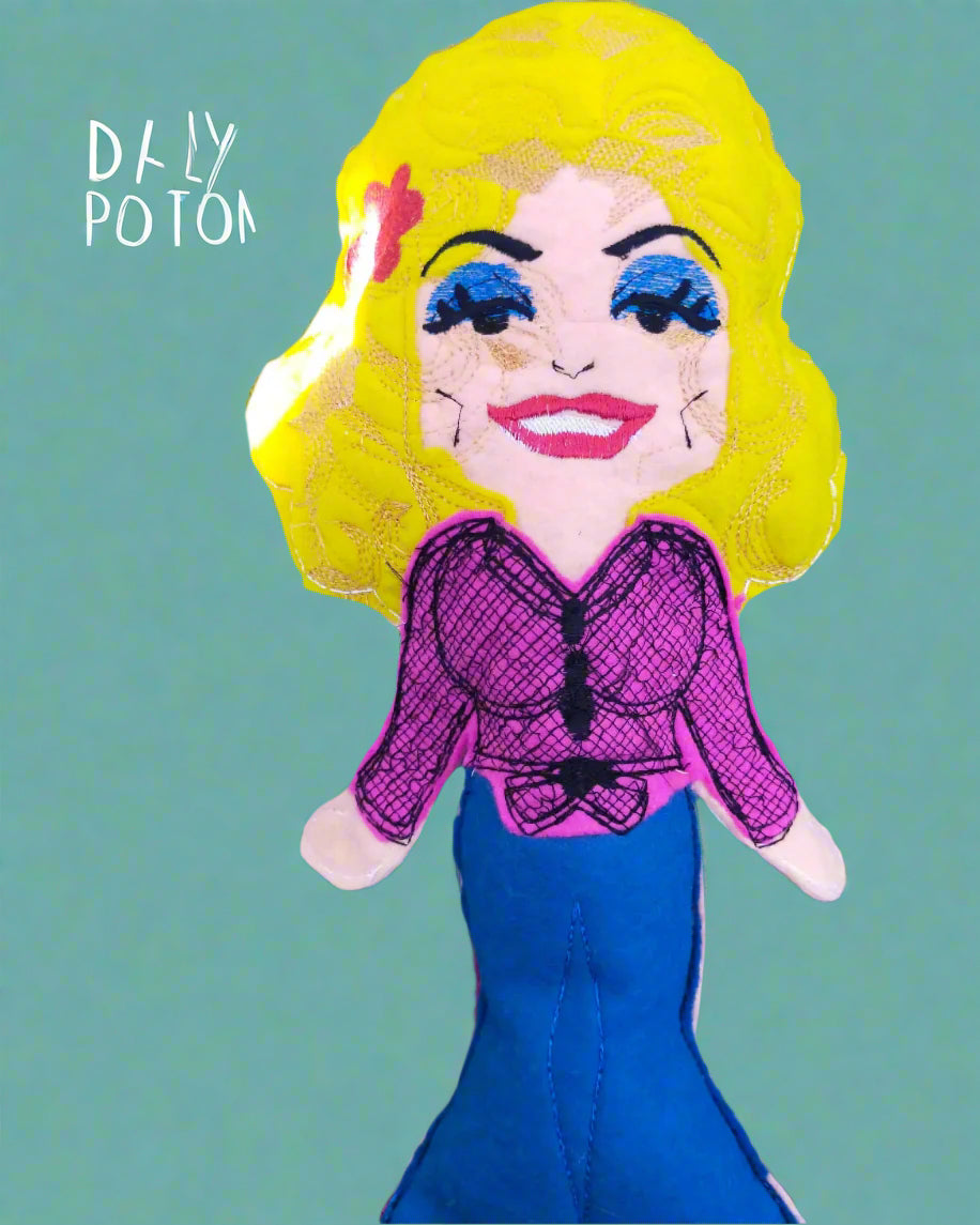 This is a Dolly Parton  stuffed toy. She is wearing jeans and a pink shirt and is available in 4 sizes. Made by Not Your Nana in Dunedin, New Zealand.