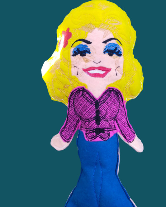 This is a Dolly Parton  stuffed toy. She is wearing jeans and a pink shirt and is available in 4 sizes. Made by Not Your Nana in Dunedin, New Zealand.