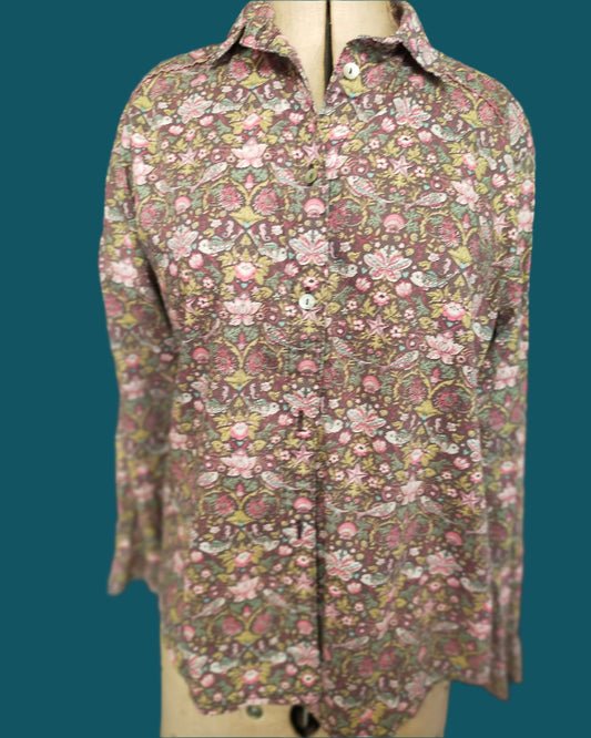 This is a classic styled shirt made from Liberty tana lawn. it is brownwith a ppretty floral pattern which includes a small fish. It features piped shoulder seams and shell buttons
