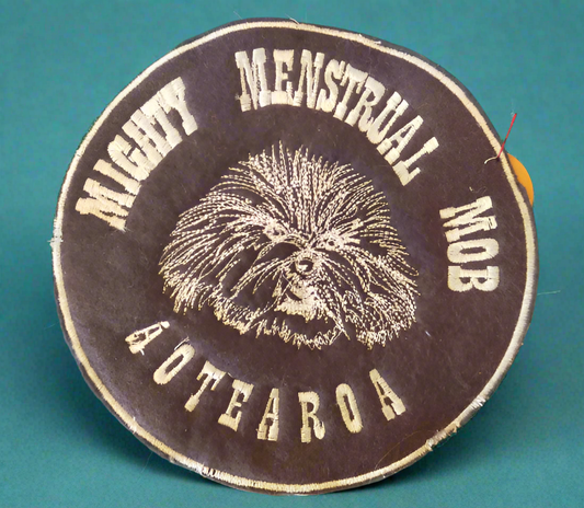 Circular patch with 'Mighty Menstrual Mob Aotearoa' text and a small white fluffy dog
