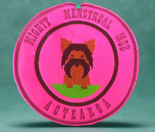 This is a patch with the text "Mighty menstrual mob Aotearoa" and a mall dog. Made by NortYour Nana, Dunedin, New Zealand