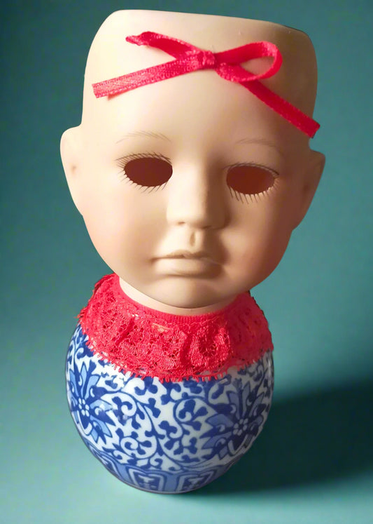 Doll head tealight with a red bow and blue and white patterned jar base.  Made by Not You Nana in Dunedin, New Zealand