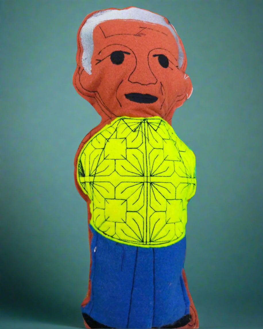 Toy figure of an elderly person wearing a bright yellow shirt with a pattern on a solid background