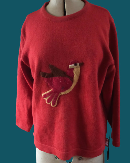 This is a rusty orange wool sweater with a vintage felt fantail on the front