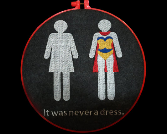 This is an embroidery of the symbol for a woman's toilet. The symbol is repeated and in the second one the dress has transformed into a superwoman cape. Made by Not Your Nana in Dunedin, New Zealand.