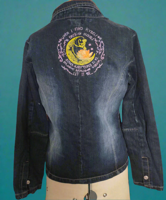Denim jacket with a embroidered design on a mannequin in a room setting.