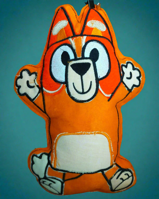 Orange plush toy with a cartoon face on a tiled floor