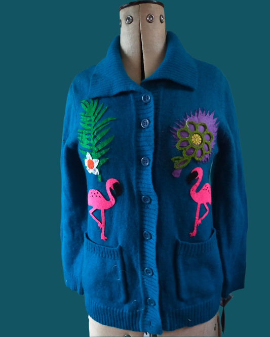 This is a peacock blue cardigan embellished with flower and flamingos. Made by not your nana in Dunedin New Zealand