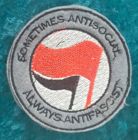 A round patch featuring the words "sometimes antisocial, always antifascist". Made by Not Your Nana, Dunedin, New Zealand