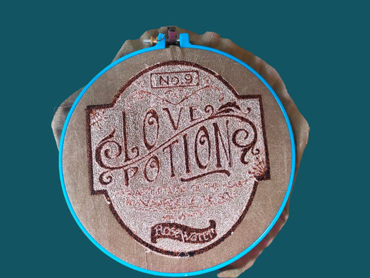 This is a sepia embroidery of a bottle label with the word s Love potion number 9. Made by ot Yout Nana ind Dunedin, New Zealand