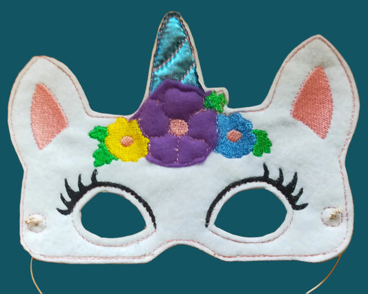 This white unicorn mask has a blue horn surrounded by flowers. Made by Not Your Nana in Dunedin. New Zealnd